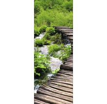 Houten loopbrug over een beek in een groen landschap