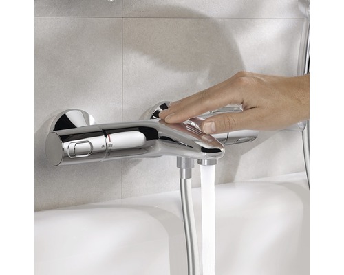 Opname van een hand die een verchroomde douchekraan bedient, waar water uit stroomt.