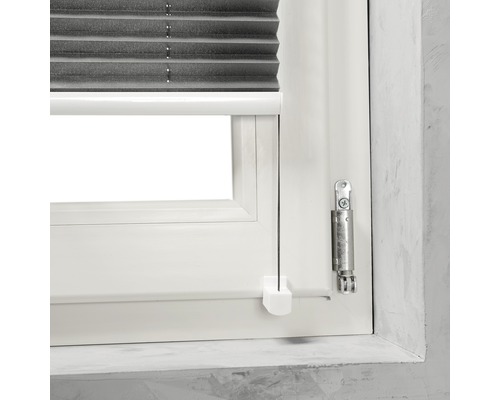 Detailopname van een raam met een grijs plisségordijn en bedieningselementen