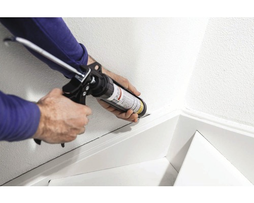 Ambachtsman gebruikt een kitpistool om een wand af te dichten