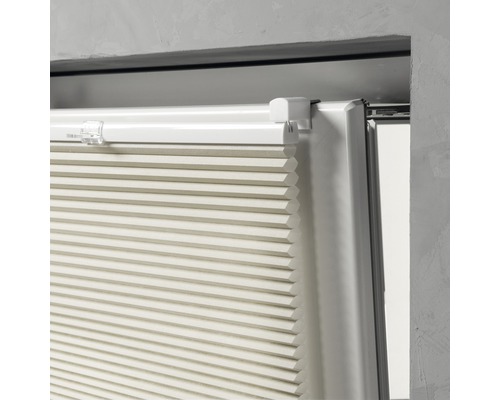 Close-up van een beige plisségordijn bij het raam