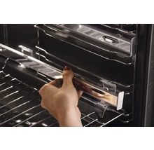 Een hand schuift een telescopische rail in een oven.