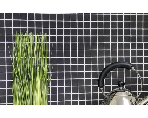 Decoratieve groene sprieten en een waterketel voor een wand met mozaïektegels