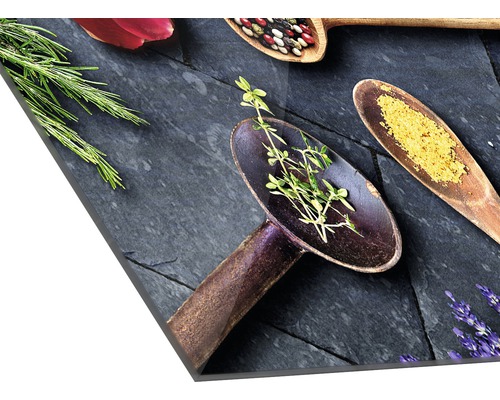 Decoratieve keukenafbeelding met kruiden en specerijen in houten lepels op een leistenen plaat