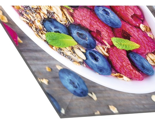 Close-up van een kom met muesli, frambozen, blauwe bessen en munt op een houten tafel