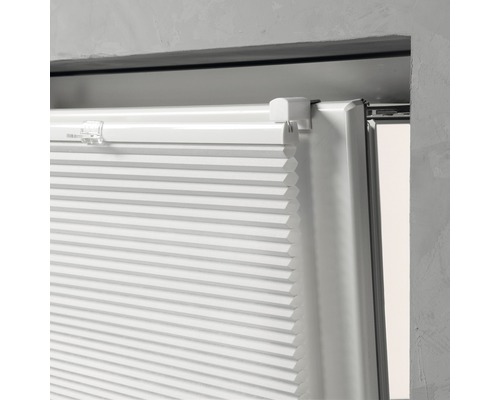 Detailopname van een witte plisségordijn op een raam