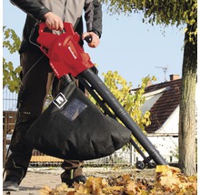 Een man gebruikt een Einhell bladzuiger in de tuin.
