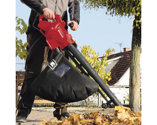 Een man gebruikt een Einhell bladzuiger in de tuin.