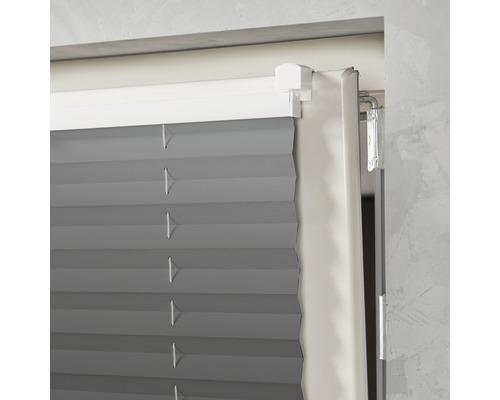 Detailopname van een grijs plisségordijn aan het raam.