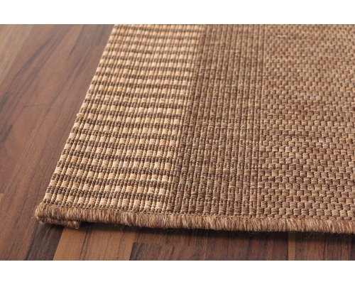 Detailopname van een geweven tapijt op een houten vloer