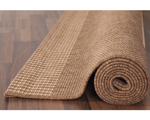 Opgerolde vloerkleed van natuurlijke vezels op een houten vloer