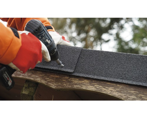 Persoon bevestigt bitumineuze dakshingle met accuschroevendraaier