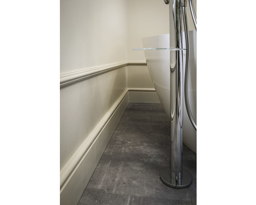 Detail van een badkamer met een vrijstaand bad, wandbekleding en vloertegels.