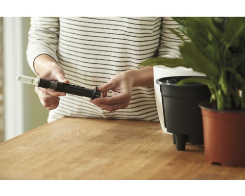 Een persoon monteert een vochtigheidssensor voor bloempotten.