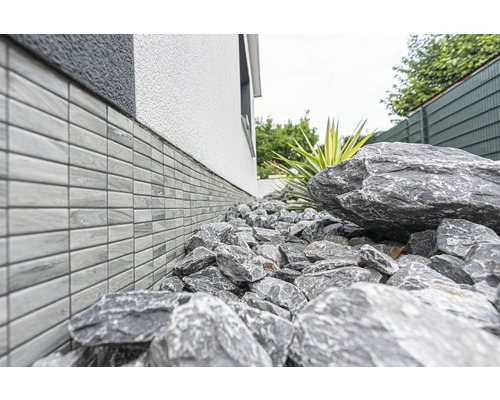 Gevel met plintbekleding en stenen in de tuin