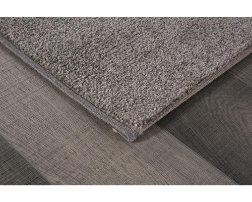 Detailweergave van een grijs tapijt met korte pool op een houten vloer