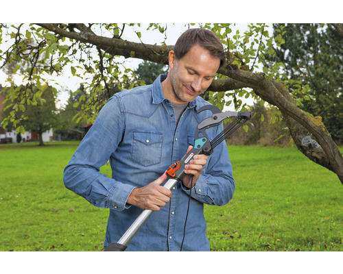 Een man bedient een takkenschaar in de tuin.