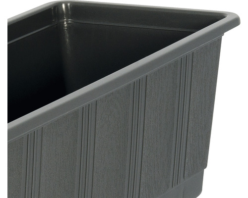Detailopname van een grijze plantenbak met een geribbelde textuur.