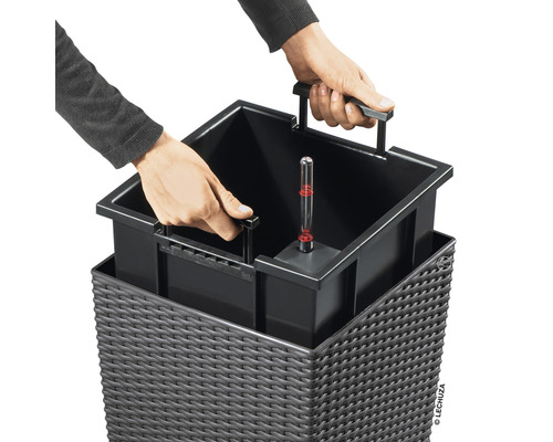 Persoon plaatst planteninzet met waterniveau-indicator in een plantenbak.