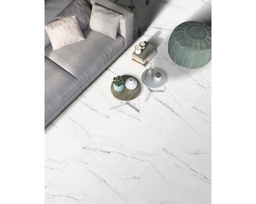 Lichte woonkamer met vloertegels in marmerlook, bank en bijzettafels.