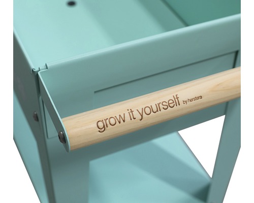 Detailweergave van een kruidenwagen met houten handgreep en de tekst Grow it yourself by herstera