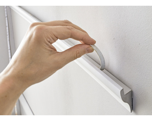 Decoratieve lijst met plakband aan de muur bevestigen