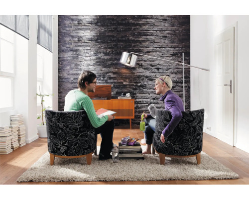 Woonkamer met twee personen in fauteuils, staande lamp en decoratie op een tapijt