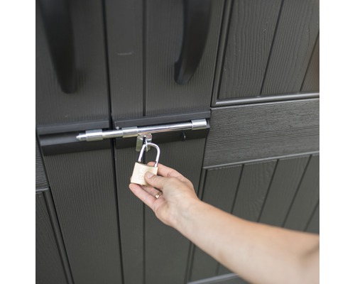 Een persoon sluit een tuinhuisje af met een hangslot.