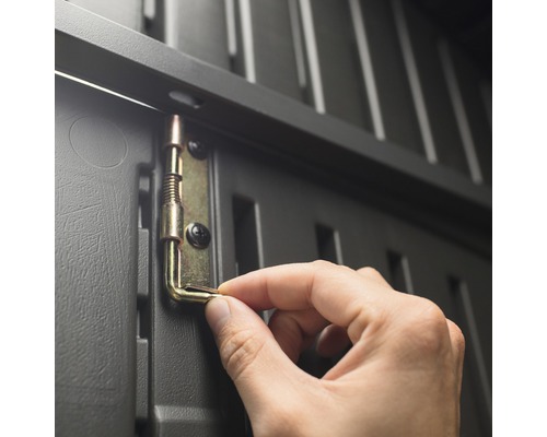 Detailopname van een hand die een metalen grendel bevestigt aan een grijze kunststof kast.