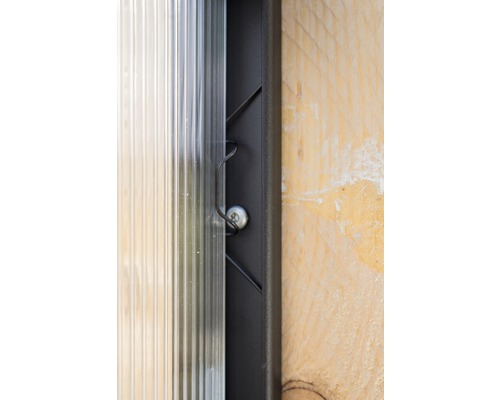 Detailopname van een transparante kanaalplaat, bevestigd met een schroef en een bevestigingsclip aan een frame