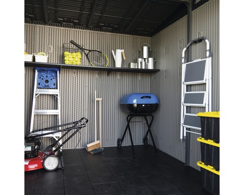 Binnenaanzicht van een tuinhuis met planken, tuingereedschap en gereedschap.