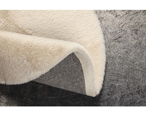 Detailopname van een beige hoogpolig tapijt met een textielen rug