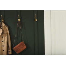 Scene met een trenchcoat en een handtas opgehangen aan gouden wandhaken