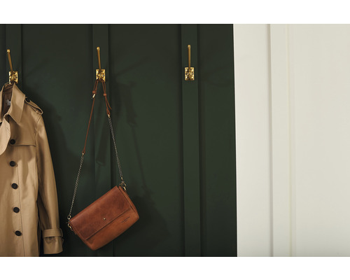 Scene met een trenchcoat en een handtas opgehangen aan gouden wandhaken