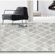 Grijs tapijt met ruitpatroon in een woonkamer met fauteuil en open haard.