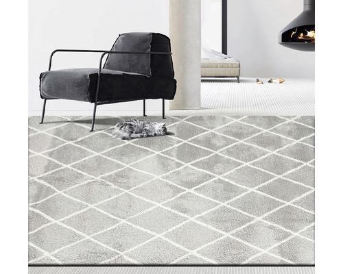 Grijs tapijt met ruitpatroon in een woonkamer met fauteuil en open haard.