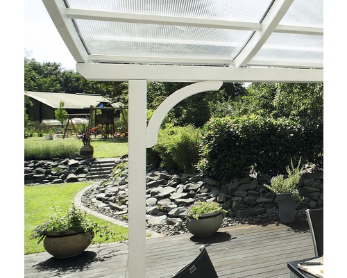 Gedetailleerd aanzicht van een terrasoverkapping met wit frame en transparant dak in een tuin.