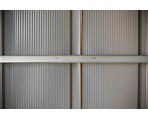 Detail van een grijze metalen wand met verticale ribbels en horizontale versteviging