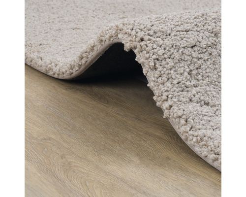 Detailopname van een beige badmat op een houten vloer