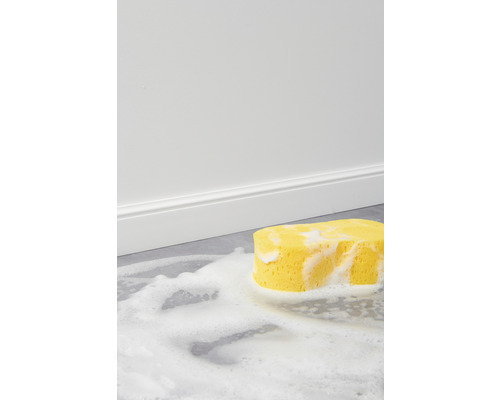 Gele schoonmaakspons met schuim op een vloer