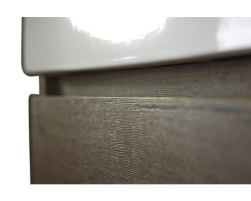 Detailopname van een wastafelonderkast met houtlook en keramische wastafel