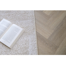 Scene met een boek op een vloerkleed en een lichte houten vloer in visgraatmotief