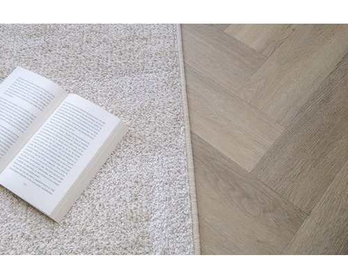 Scene met een boek op een vloerkleed en een lichte houten vloer in visgraatmotief