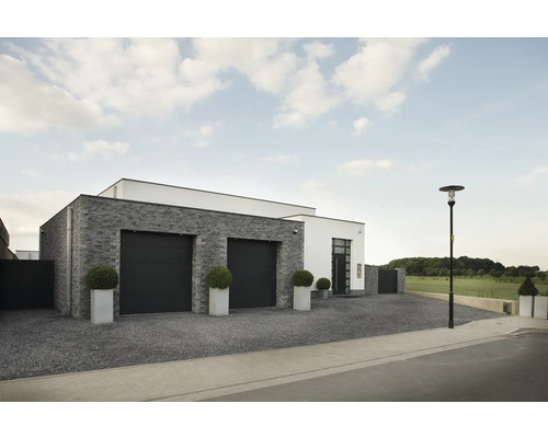 Buitenkant van een modern huis met garage, stenen gevel en verharde oprit