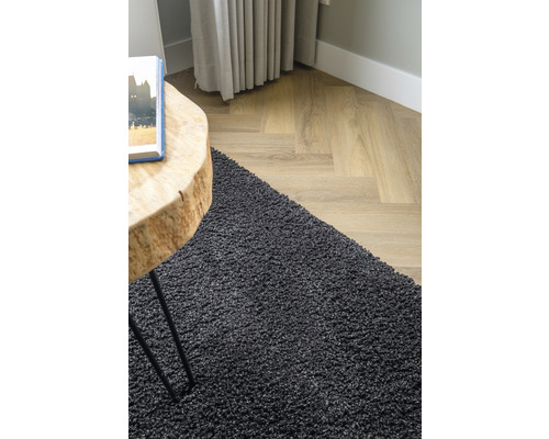 Detailopname van een zwart tapijt in de woonkamer met houten vloer en houten tafel