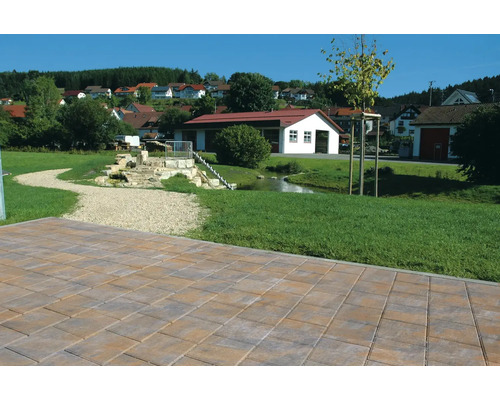 Bestrating in de buitenruimte met een beekje en huizen op de achtergrond