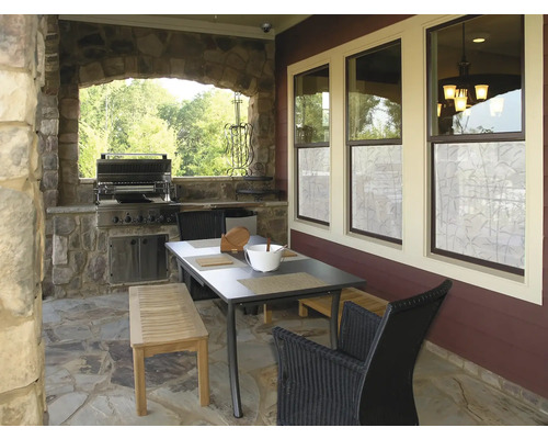 Overdekt terras met barbecue, tafel, bank en stoelen.