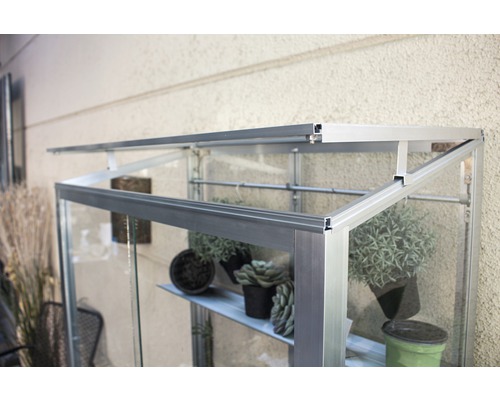 Close-up van een kas met aluminium frame en planken voor planten.