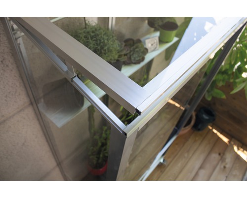 Detailopname van een kas met aluminium frame en planten