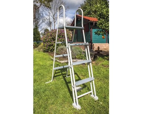 Metalen zwembadladder met vier treden in de tuin